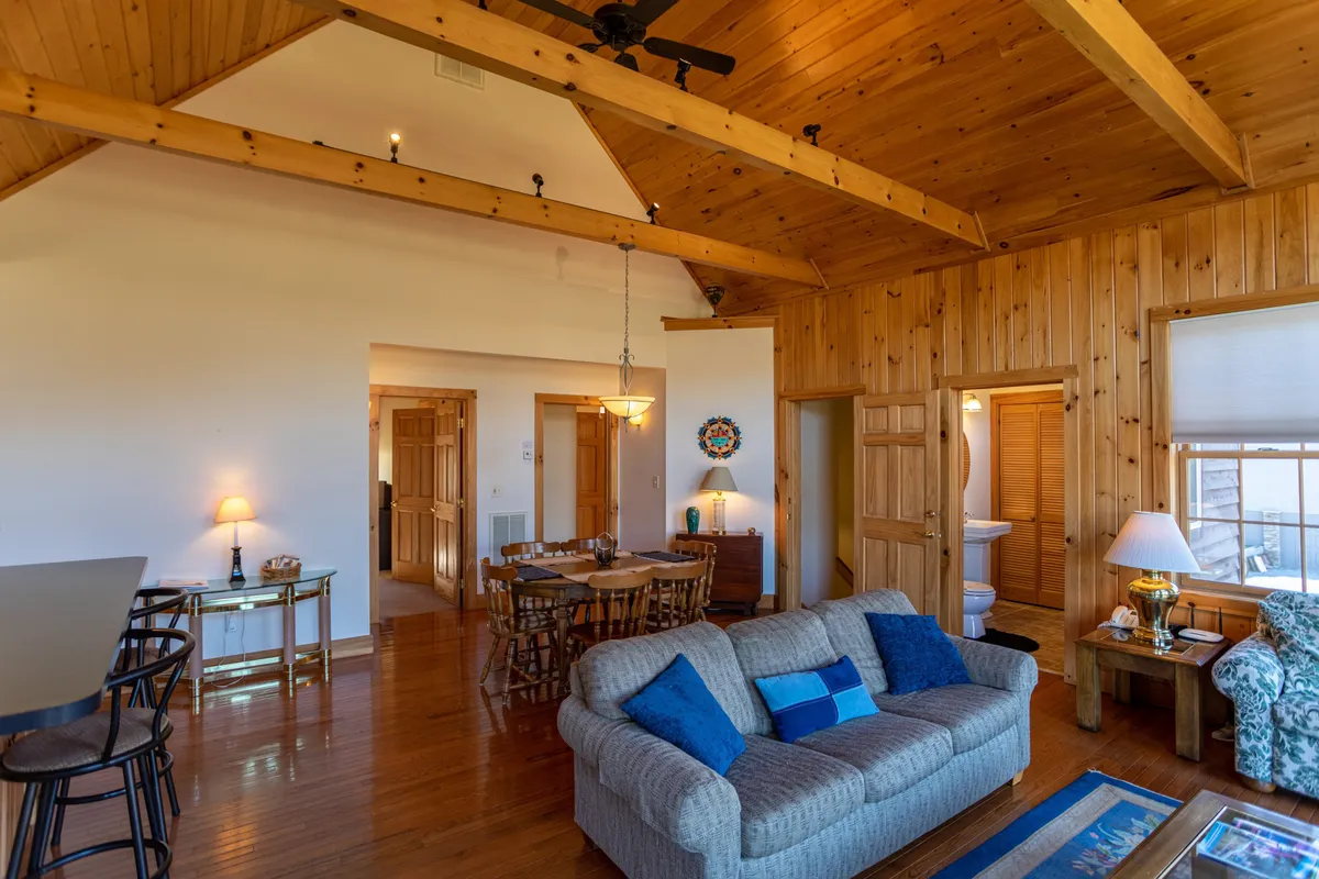 A comfortable living and dining area with a soft, inviting sofa adorned with blue pillows, a wooden dining table for shared meals, and decorative touches that add warmth. The room is designed for relaxation, entertaining, and making lasting memories.